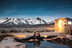 Man relaxing in an outdoor water hole by mountains